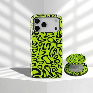 May include: A neon green and black phone case with a matching phone grip. The case and grip feature a repeating abstract design with the word "SOL7" visible. The phone case has a camera cutout.