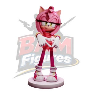 Könnte beinhalten: Eine rosa Figur von Amy Rose aus der Sonic the Hedgehog-Serie. Sie formt ein Herz mit ihren Händen und trägt ein rotes Kleid, rosa Schuhe und ein gelbes Armband. Die Figur steht auf einem runden Sockel mit dem Text "BAM Figures" im Hintergrund.
