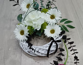 Corona de flores de luto: margaritas blancas, hortensias, calas y detalles en negro.