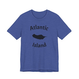Puede incluir: Una camiseta de manga corta en color azul jaspeado que presenta un gráfico negro de la silueta de una isla entre las palabras Atlantic e Island, impresas en una fuente negra negrita sin remates en la parte frontal.