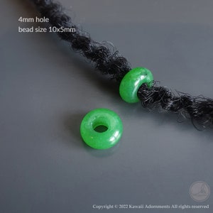 May include: Two bright green, donut-shaped beads with a 4mm hole and a 10x5mm bead size are displayed. The beads are shown on a dark, textured surface. The text "4mm hole bead size 10x5mm" is visible.