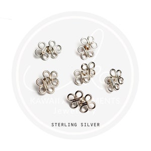 May include: Six silver flower-shaped clasps, each with four loops, arranged in a circle on a white background. The text "STERLING SILVER" is visible below the clasps.