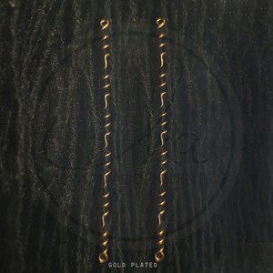 May include: Two gold-plated earring chains. Each chain is made up of small, curved links joined by straight bars. The chains have a loop at each end for attachment. The text "GOLD PLATED" is at the bottom of the image.