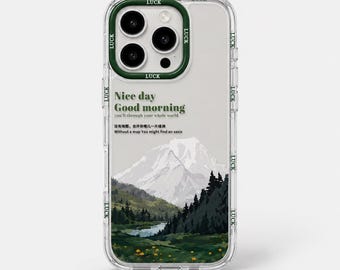 Op de afbeelding: Transparante telefoonhoes met een groene rand en het woord "LUCK" herhaald rond de randen. De hoes heeft een berglandschapontwerp met de tekst "Nice day Good morning" en andere zinnen.