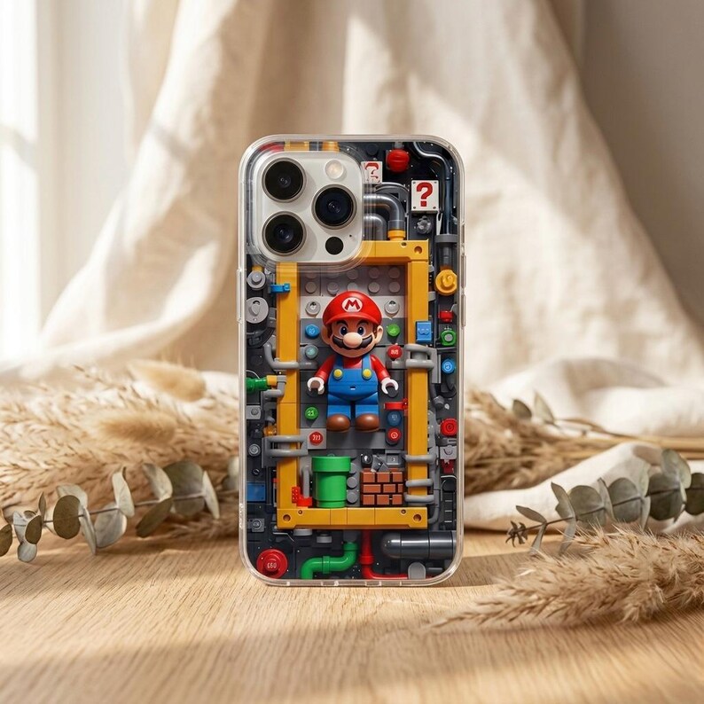 May include: Clear phone case featuring a colorful design of a Lego-style Mario figure inside a yellow and gray structure. The case has a clear border and a detailed, playful aesthetic, with a brick wall and green pipes.