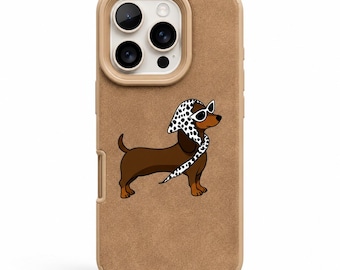Op de afbeelding: Een bruin-beige iPhone-hoesje met een cartoon teckel met een zonnebril en een polkadot sjaal. De hoes heeft een bruine textuur met een beige cameraring.