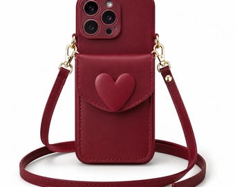 Op de afbeelding: Bordeaux telefoonhoesje met een hartvormig accent op de voorzak. De hoes heeft een bijpassende bordeauxrode band en goudkleurige hardware. De telefoonhoes is ontworpen om een smartphone te bevatten en heeft een crossbody band.