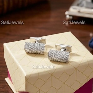 Może przedstawiać: Zestaw trzech ceramicznych kubków z nakrapianą, kremową glazurą. Każdy kubek ma inny ręcznie malowany wzór: niebiesko-zielony liść, żółty kwiat i czerwona jagoda. Kubki mają prosty, zaokrąglony kształt.