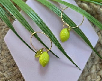 May include: A pair of gold-toned hoop earrings, each featuring a small, textured, bright lime-green lemon charm. One earring includes a tiny, translucent green leaf accent attached to the hoop alongside the lemon charm, while the other features a single lemon.