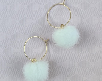 May include: A pair of gold-toned hoop earrings, each featuring a single, fluffy white pom-pom charm suspended from the bottom of the circular wire frame. The earrings are simple in design, showcasing a thin metallic hoop and a soft, round, textured white accent that hangs freely from the base of each hoop.