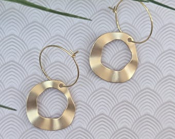 May include: A pair of gold-toned hoop earrings featuring a thin circular wire post attached to a larger, flat, wavy-edged circular pendant. The metal has a smooth, matte finish, and the design consists of two distinct parts connected by a small loop.