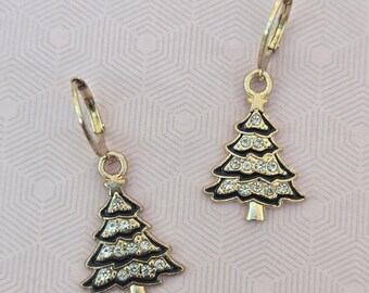 May include: A pair of gold-tone leverback earrings featuring a Christmas tree charm. Each tree is outlined in gold metal with black enamel detailing and embedded with clear, sparkling rhinestones arranged in three horizontal rows.