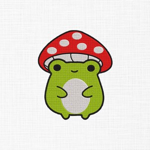 May include: A cute cartoon frog with a red mushroom cap featuring white polka dots. The frog is green with a white belly and black eyes. The design is likely for embroidery or a similar craft project.