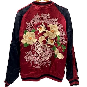 Könnte beinhalten: Eine rote Satin-Bomberjacke mit schwarzen Ärmeln sowie geripptem Kragen, Bündchen und Saum. Die Rückseite zeigt eine detaillierte Stickerei eines weißen Drachen und große cremefarbene, rote und grüne Blumenmuster, darunter Chrysanthemen.
