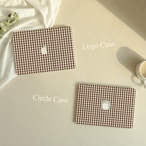 May include: Two laptop cases featuring a brown and white gingham pattern. The top case, labeled Logo Case, has a cutout for the Apple logo. The bottom case, labeled Circle Case, features a circular cutout for the Apple logo in the center.