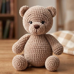 Könnte beinhalten: Handgefertigter, hellbrauner Häkelteddybär mit strukturierter Oberfläche. Der Bär hat eine braune Nase und schwarze Augen und sitzt auf einer Holzoberfläche. Die Arme und Beine des Bären sind ebenfalls gehäkelt.
