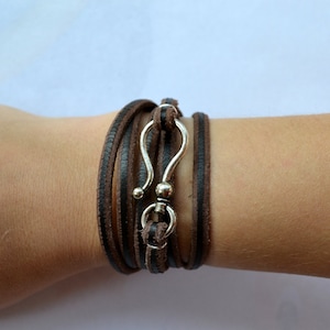 May include: A brown leather wrap bracelet with a silver hook clasp.