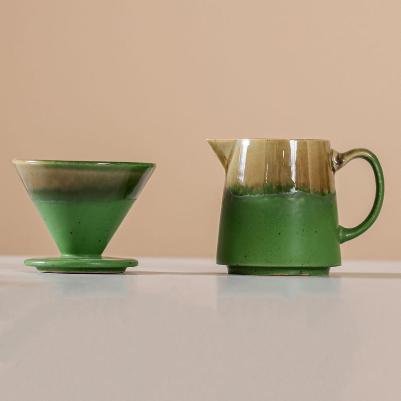 Peut inclure: Un ensemble verseur &agrave; caf&eacute; et pichet en c&eacute;ramique. Le verseur est en forme de c&ocirc;ne avec un gla&ccedil;age vert et marron. Le pichet a une anse et un bec, avec un gla&ccedil;age vert et marron similaire. L'ensemble est con&ccedil;u pour pr&eacute;parer du caf&eacute;.