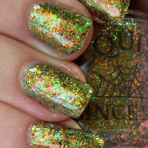 Könnte beinhalten: Nahaufnahme von manikürten Nägeln mit schimmerndem grün-goldenen Glitzer-Nagellack. Der Lack hat einen mehrfarbigen, irisierenden Effekt mit orangefarbenen, blauen und gelben Flecken. Die Nägel sind oval geformt und der Lack ist glatt aufgetragen.