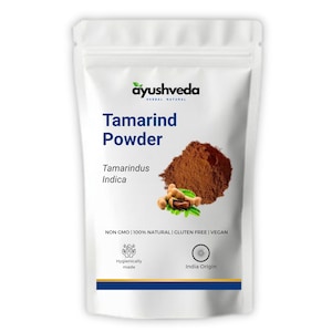 Puede incluir: Bolsa blanca de polvo de tamarindo con la marca "ayushveda". El texto "Tamarind Powder" se muestra de forma destacada. Se muestra un montón de polvo marrón y vainas de tamarindo. El texto "NON GMO | 100% NATURAL | GLUTEN FREE | VEGAN" también es visible.