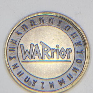 Brass coin engraved with WARrior text, blue tarnish accents and decorative rim, coin engraving files example.