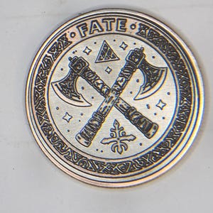 Round test coin with central geometric motif and textured fill, demonstrating laser parameters guide results.