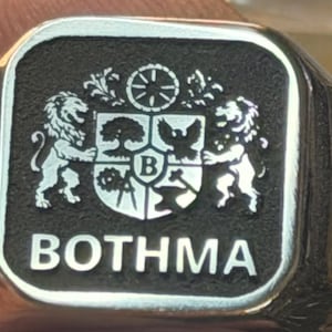 Polished signet plate engraved with detailed coat of arms and BOTHMA text, square metal engraving sample.