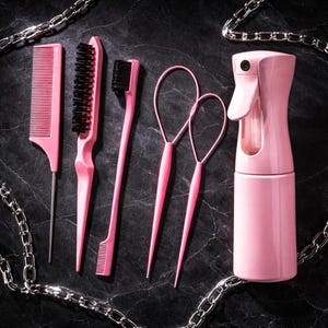 May include: A set of pink hair styling tools, including combs, brushes, loop tools, and a spray bottle. The tools are arranged on a dark surface, with a silver chain in the background. The set is designed for hair care and styling.