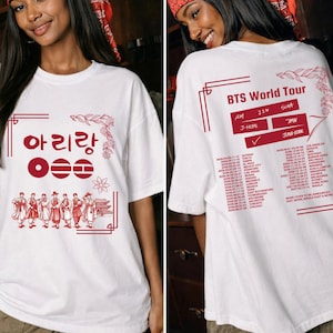 Könnte beinhalten: Weißes T-Shirt mit roten Grafiken. Auf der Vorderseite befinden sich koreanischer Text und Figuren in traditioneller Kleidung. Auf der Rückseite steht "BTS World Tour", die Namen der Mitglieder und eine Liste der Tourdaten und -orte.
