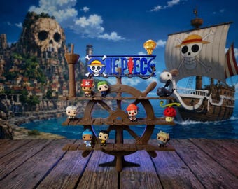 Puede incluir: Un expositor de plástico marrón con forma de timón de barco que cuenta con tres estantes horizontales con nueve pequeñas figuras de vinilo. La parte superior del soporte muestra el logotipo de One Piece en azul y blanco. Las figuras tienen colores de pelo y atuendos variados.