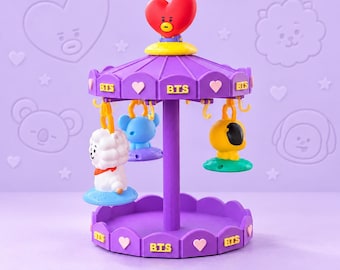 Peut inclure: Un présentoir rotatif violet de style carrousel avec l'inscription BTS et des cœurs. Le sommet est surmonté d'une figurine en forme de cœur rouge. Trois petites figurines colorées sont suspendues à des crochets jaunes.