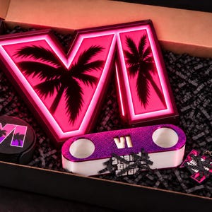 May include: A gift box containing a large illuminated sign with the Roman numeral VI and palm tree silhouettes, a round coaster set with the VI logo, a purple and white dual-hole holder with the VI logo, and a keychain with the VI logo.
