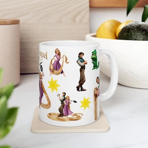 Puede incluir: Taza de cerámica blanca con ilustraciones de personajes de la película Enredados, incluyendo a Rapunzel, Flynn Rider y Pascal. La taza tiene un asa curva y está decorada con imágenes del sol. La palabra "Tangled" está impresa en la taza.