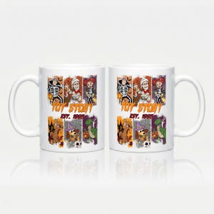Könnte beinhalten: Zwei weiße Keramikbecher mit einer bunten Halloween-Grafik und kostümierten Toy Story-Figuren. Das Design enthält den Text Toy Story Est. 1995 und zeigt Charaktere wie Woody, Buzz Lightyear und Rex, die für den Feiertag verkleidet sind.