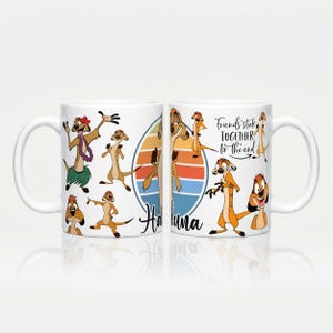Peut inclure: Un mug en céramique blanche orné de suricates de dessin animé dans diverses poses, d'un graphique en cercle de coucher de soleil rétro et du texte "Hakuna" et "Friends stick TOGETHER to the end" en polices script et sans-serif.
