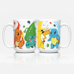 Könnte beinhalten: Zwei weiße Keramikbecher mit bunten Cartoon-Charakter-Designs. Ein Becher zeigt Charmander, Bulbasaur, Pikachu und Squirtle. Der andere Becher hat die gleichen Charaktere. Die Becher haben große Henkel und sind vor einem weißen Hintergrund platziert.