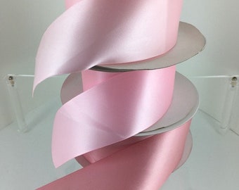 May include: Three spools of pink satin ribbon. The ribbon is wound around white cardboard spools.