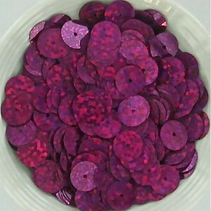 May include: A large pile of iridescent purple sequins. The sequins are round and have a hole in the center. They are perfect for crafting and decorating.