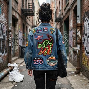 May include: A denim jacket with various patches, including a skeleton cat design, an American flag, and the text "I Love USA". The jacket is worn over black jeans and a black bag is hanging from the shoulder.