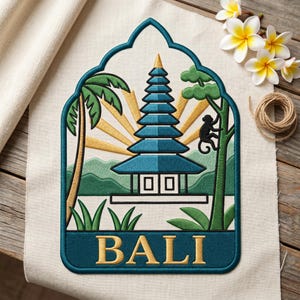 May include: Embroidered patch featuring a Balinese temple scene with a blue and gold color scheme. The design includes a pagoda, palm trees, a monkey, and the word "BALI" in gold lettering. The patch is set against a cream-colored fabric.