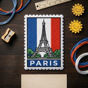 May include: A rectangular embroidered patch shaped like a postage stamp featuring the Eiffel Tower against the French flag colors of blue, white, and red. The word PARIS is stitched in white capital letters on a blue background at the bottom.
