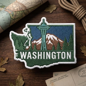 May include: Embroidered patch featuring the state of Washington with the Space Needle, mountains, and evergreen trees. The word "WASHINGTON" is stitched in white. The patch is bordered in white and set against a blue and green background.
