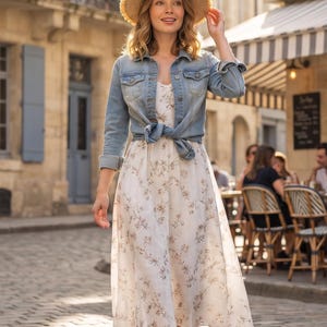 Peut inclure: Une veste en jean bleu clair nouée à la taille sur une robe midi blanche à motif floral marron délicat. La tenue comprend un chapeau de paille à larges bords avec un bord effiloché et des sandales à brides marron pour un style superposé.