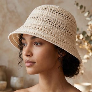 Peut inclure: Un chapeau seau en crochet de couleur crème avec un large bord. Le chapeau présente un motif ajouré, permettant une bonne aération. Un accessoire élégant pour la protection solaire et ajoute une touche bohème.