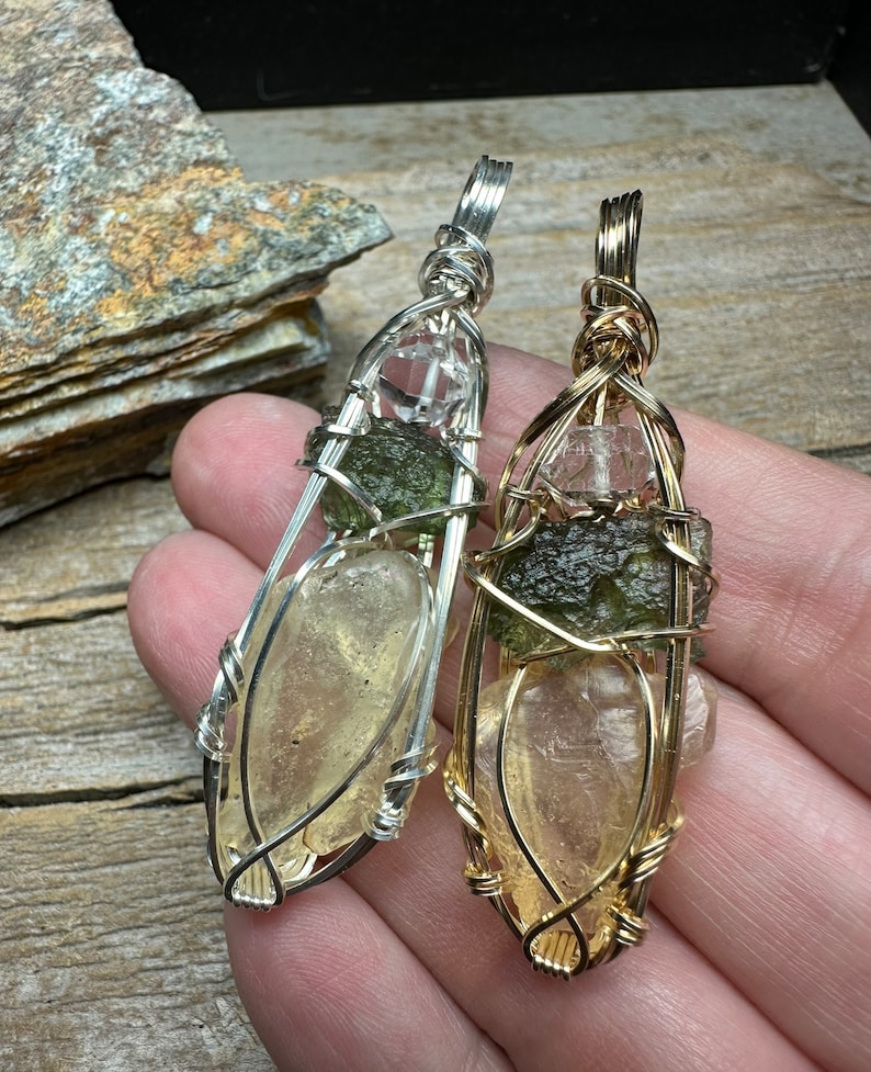 May include: Two wire-wrapped pendants with clear quartz, green aventurine, and golden healer crystals. The pendant on the left is wrapped in silver wire, and the pendant on the right is wrapped in gold wire.