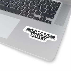Peut inclure: Un autocollant blanc avec le texte "IT WORKS WHY?" en noir, avec un graphique d'ordinateur portable de chaque côté. L'autocollant est sur un ordinateur portable argenté.
