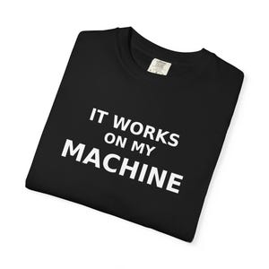 Peut inclure: T-shirt noir avec le texte blanc "IT WORKS ON MY MACHINE". Le t-shirt est plié et porte une étiquette dans le coin supérieur droit. Le t-shirt est fait d'une matière douce.