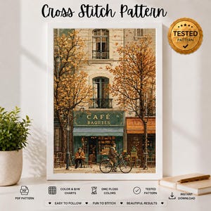 以下が含まれることがあります： CAFÉ BAGUTESというカフェ、秋の木々、自転車に乗る人が描かれたクロスステッチの図案。額装されたアートワークにはTESTED PATTERNと書かれた金色のシールがあり、PDFやDMC刺繍糸の色見本を示すアイコンが添えられています。