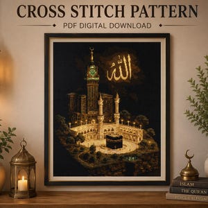 May include: A framed cross stitch pattern PDF digital download featuring an illustration of the Kaaba in Mecca with the Abraj Al-Bait clock tower in the background, illuminated by warm lights against a dark sky with gold Arabic calligraphy.