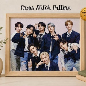 May include: A cross stitch pattern featuring a group of eight individuals in dark blue jackets and white shirts, displayed in a light wood frame. The text Cross Stitch Pattern appears at the top, with a gold circular badge labelled TESTED PATTERN.
